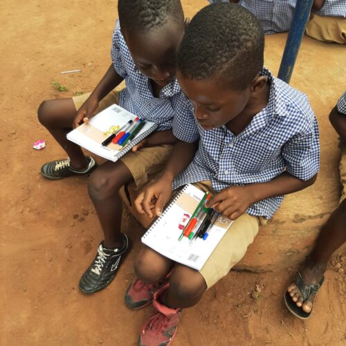 Deux enfants entrain de regarder les dons recu à l’école EPL Le Savoir Universel